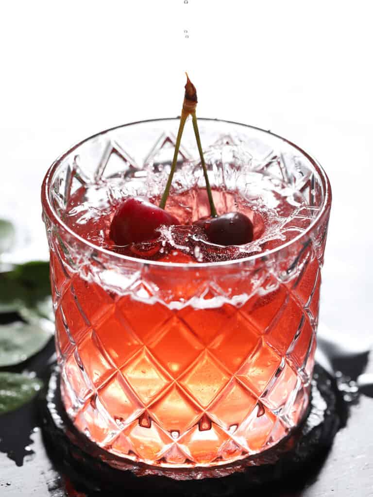 A pair of cherries splashing into a glass.