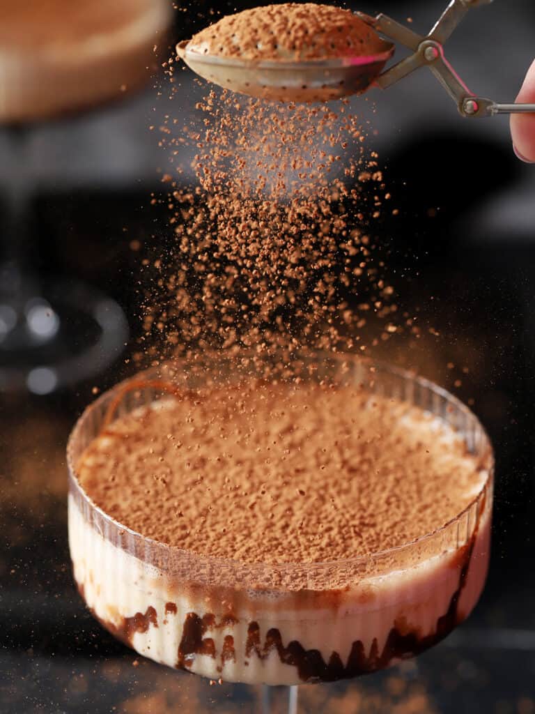 Cocoa powder being showered down onto a cocktail glass.