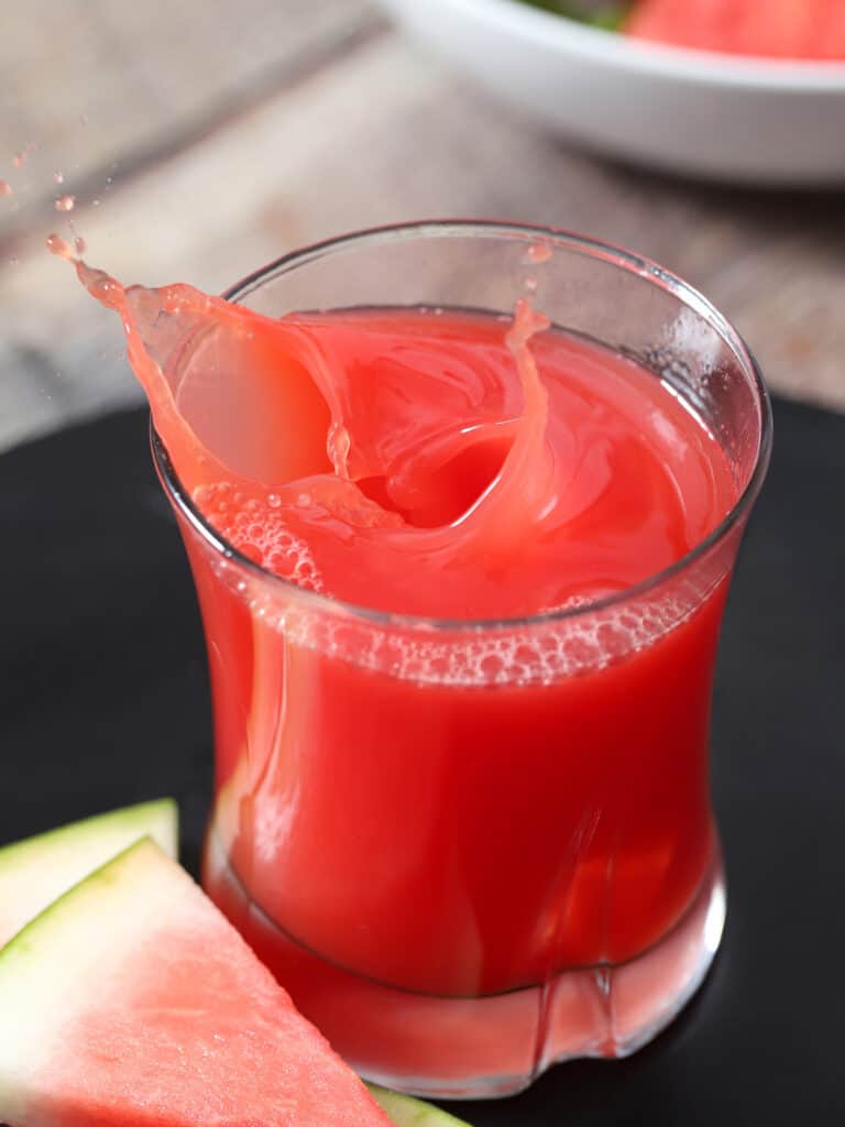 A large splash coming out of a glass of watermelon juice.