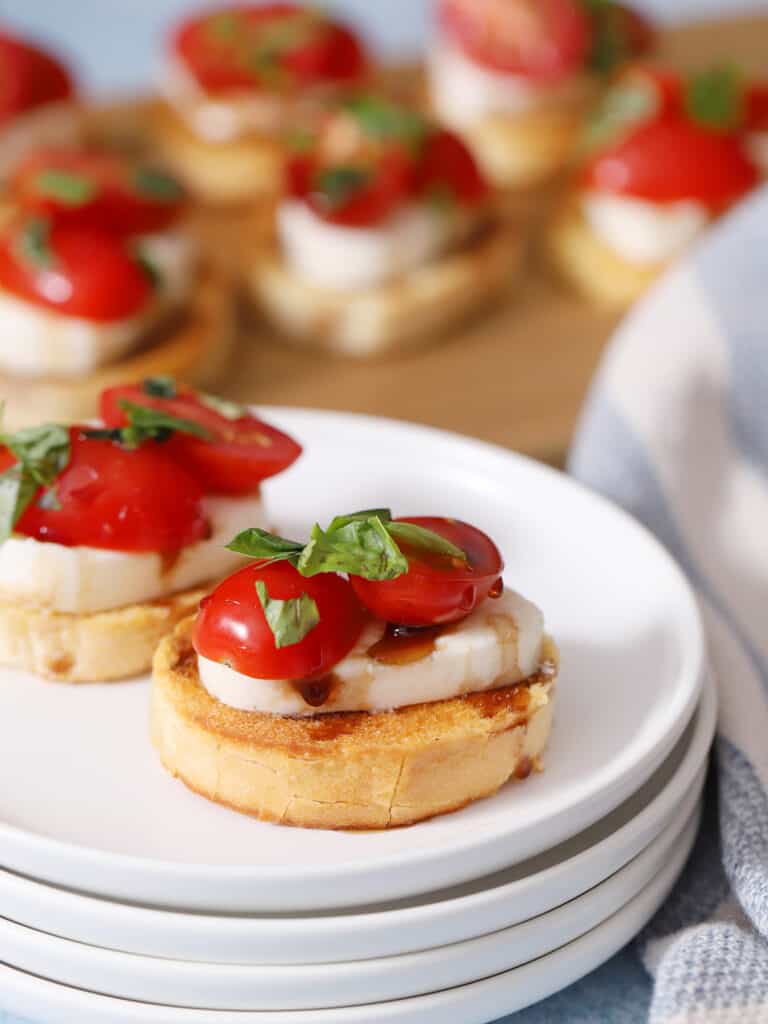 A stack of plates with crostini appetizers.