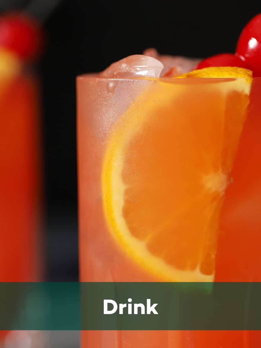 A close up of a glass filled with a red drink and orange slice. 